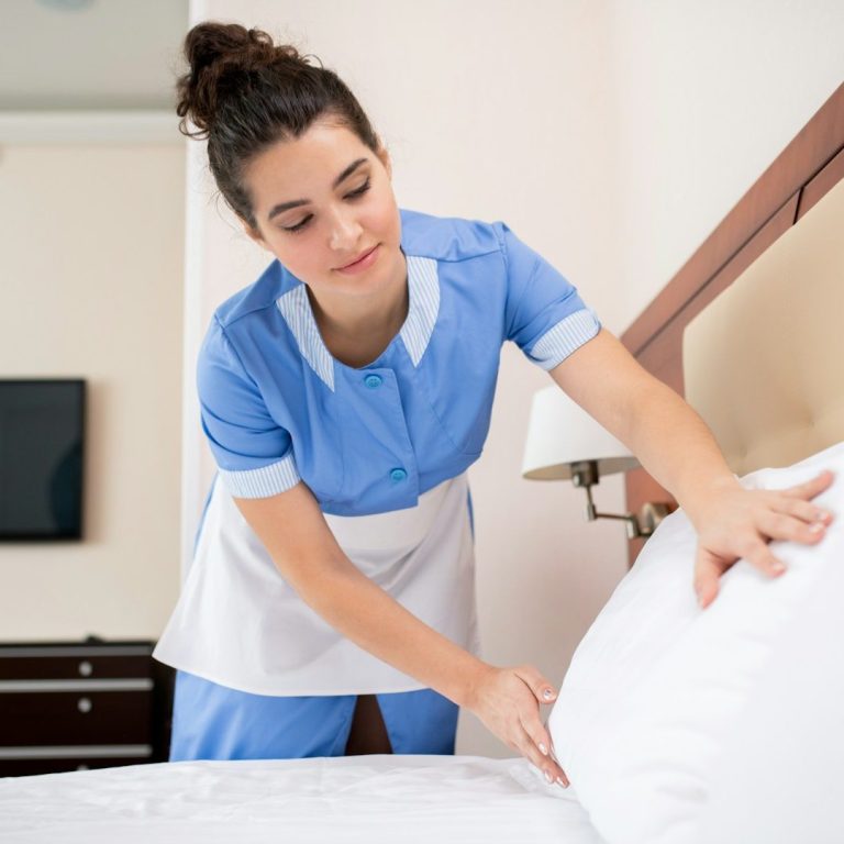 Eine Reinigungskraft macht ein Bett mit frischen Kissenbezügen.
Hotelreinigung