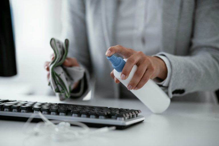 Eine Person reinigt eine Tastatur mit einem Spray und einem Tuch. Reinigungsdienst Wangen im Allgäu!