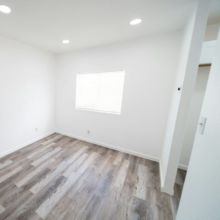 Helles, leeres Zimmer mit Holzboden und einem Fenster.
Baureinigung